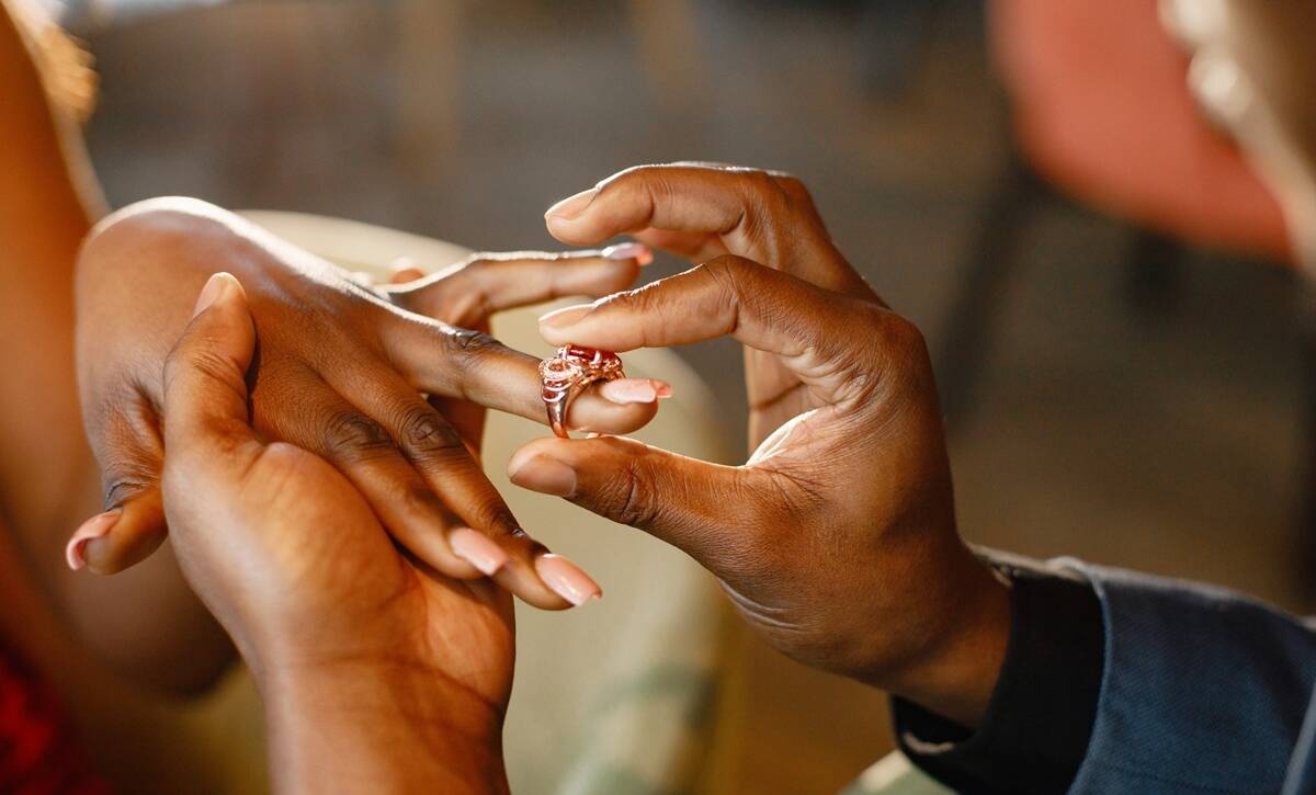 Couple holding hands with engagement ring